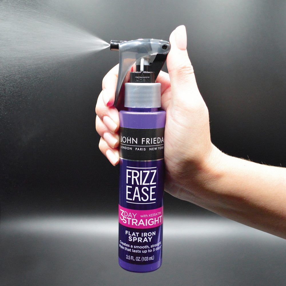 A person spraying the Frizz Ease 3 Day Straight Flat Iron Spray.