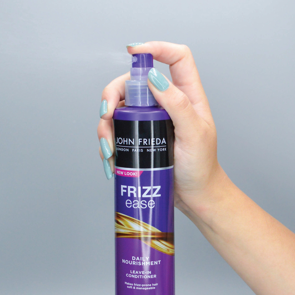 A person spraying Frizz Ease Daily Nourishment Leave-In Conditioner.