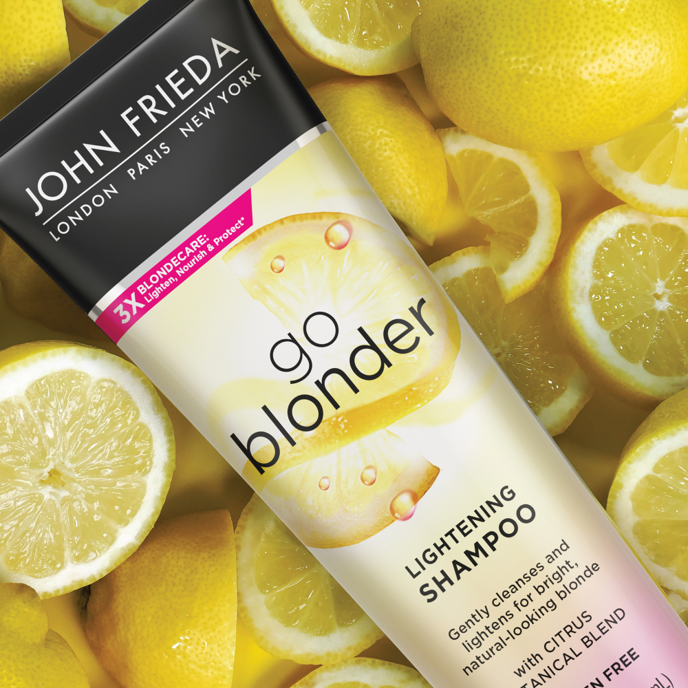 Go Blonder Lightening Shampoo bottle near lemons to represent the Citrus Tropical Blend in the product.
