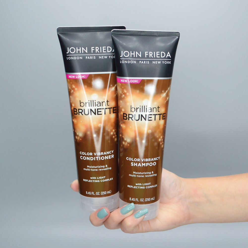 Hand holding the Brilliant Brunette Color Vibrancy Shampoo and Conditioner.